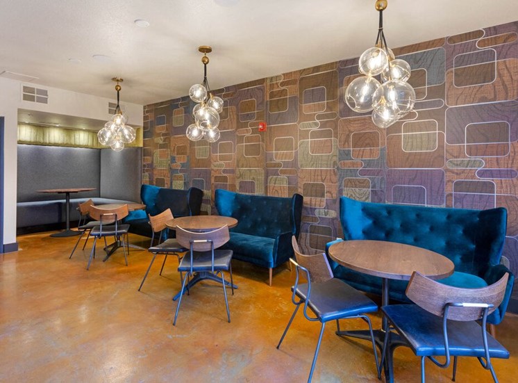Lounge Area with Contemporary Wall Print Behind Dinette Tables with Chairs and Velvet Booth Style Couches Next to Booth with Chairs